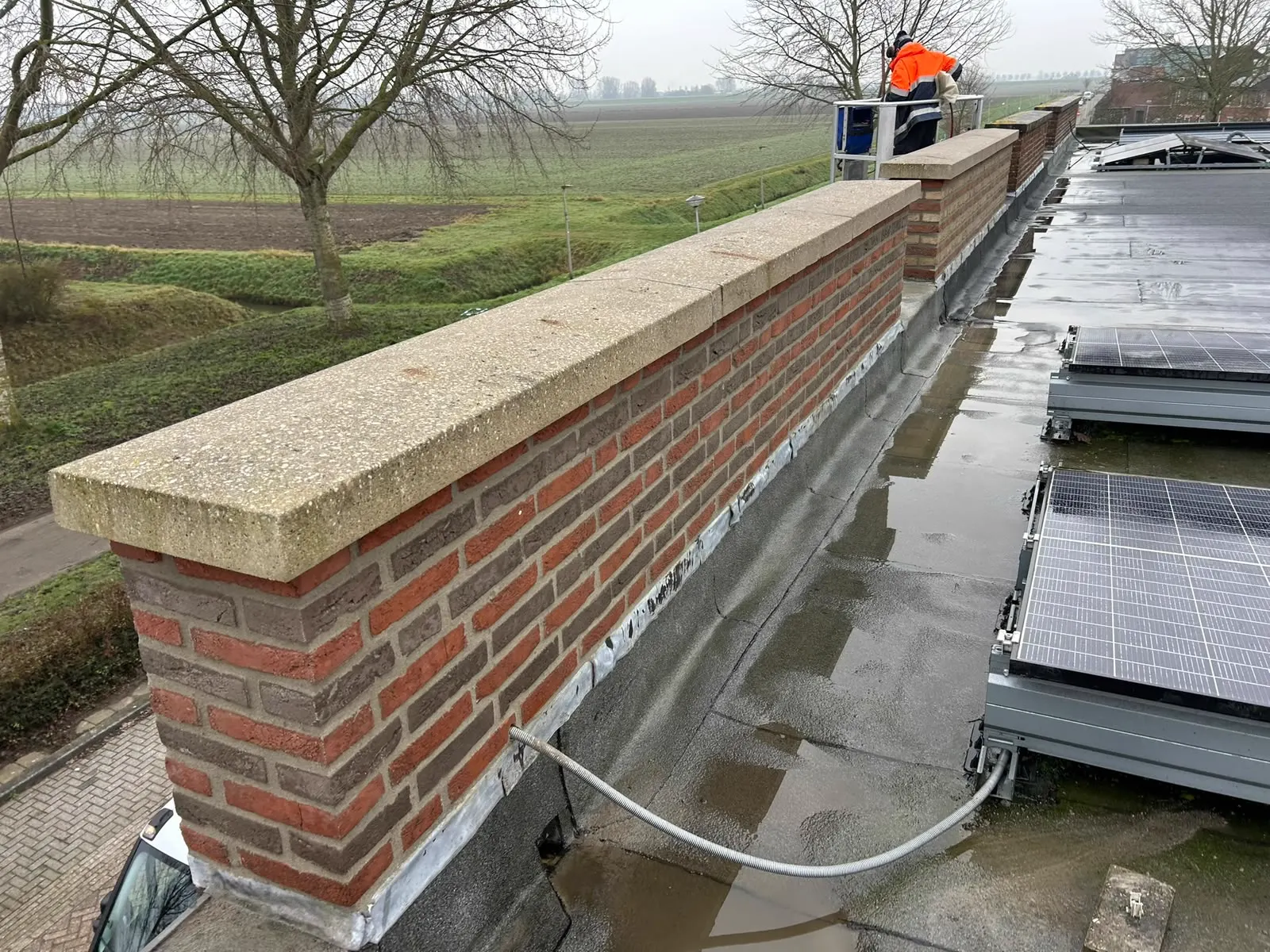 Dakopstand met betonnen muurafdekkers en loodaansluiting op een plat dak