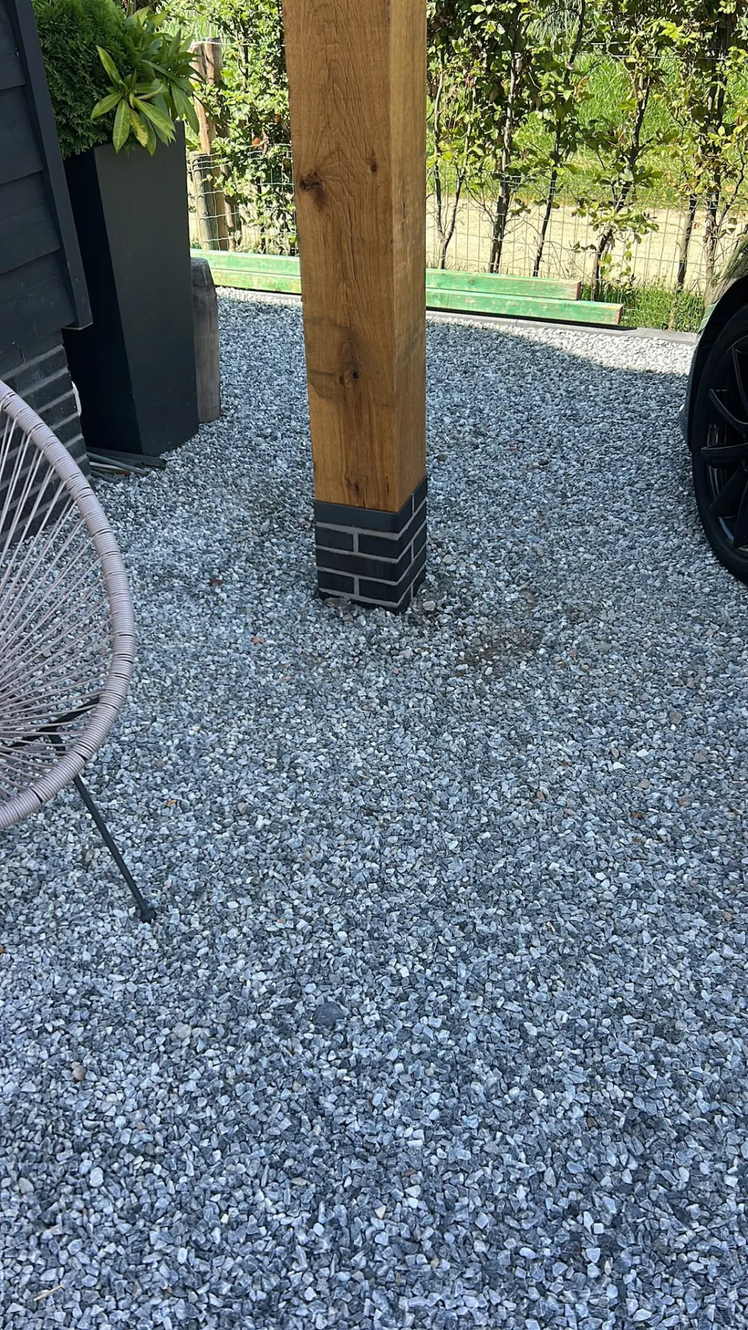 Gemetselde poer van steenstrips rond een houten pergolapaal