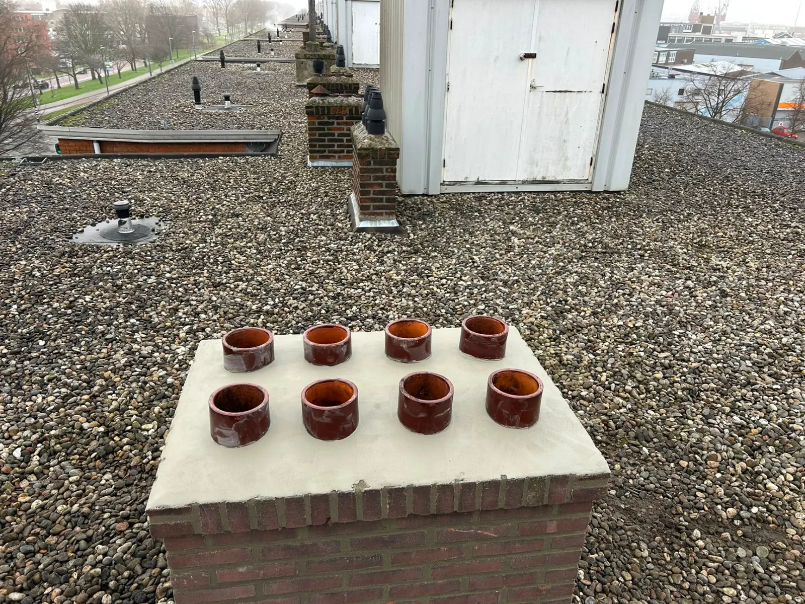 Vernieuwde schoorsteen met acht potten op een grinddak