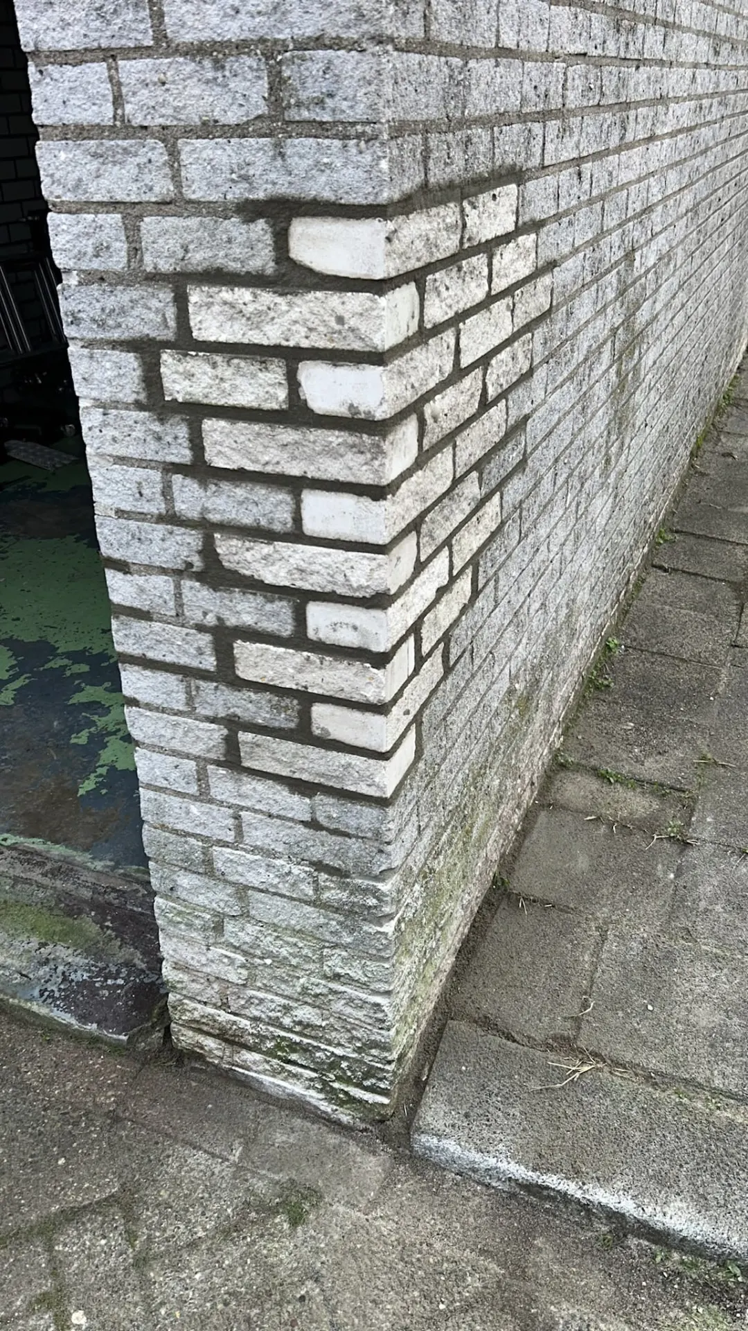 Witte bakstenen gevelhoek met inboetwerk en nieuwe stenen