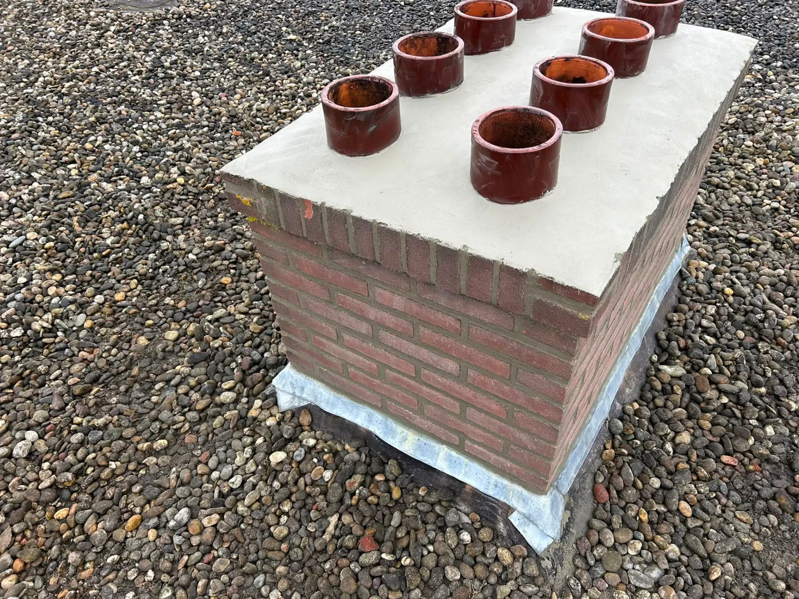 Afgewerkte schoorsteen met nieuw voegwerk en gestucte afdekking