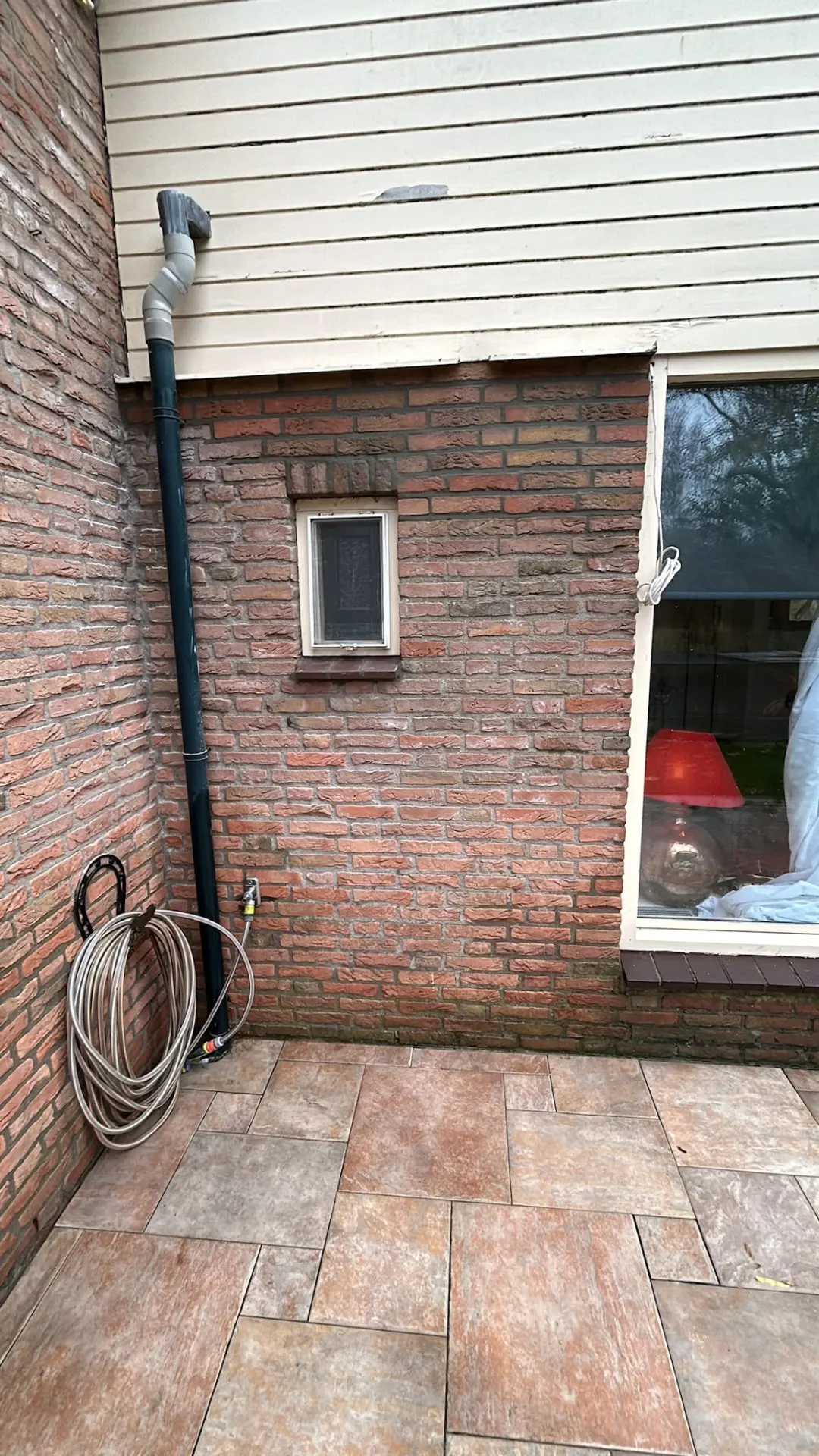 Rode bakstenen achtergevel met terras voor de start van de renovatie