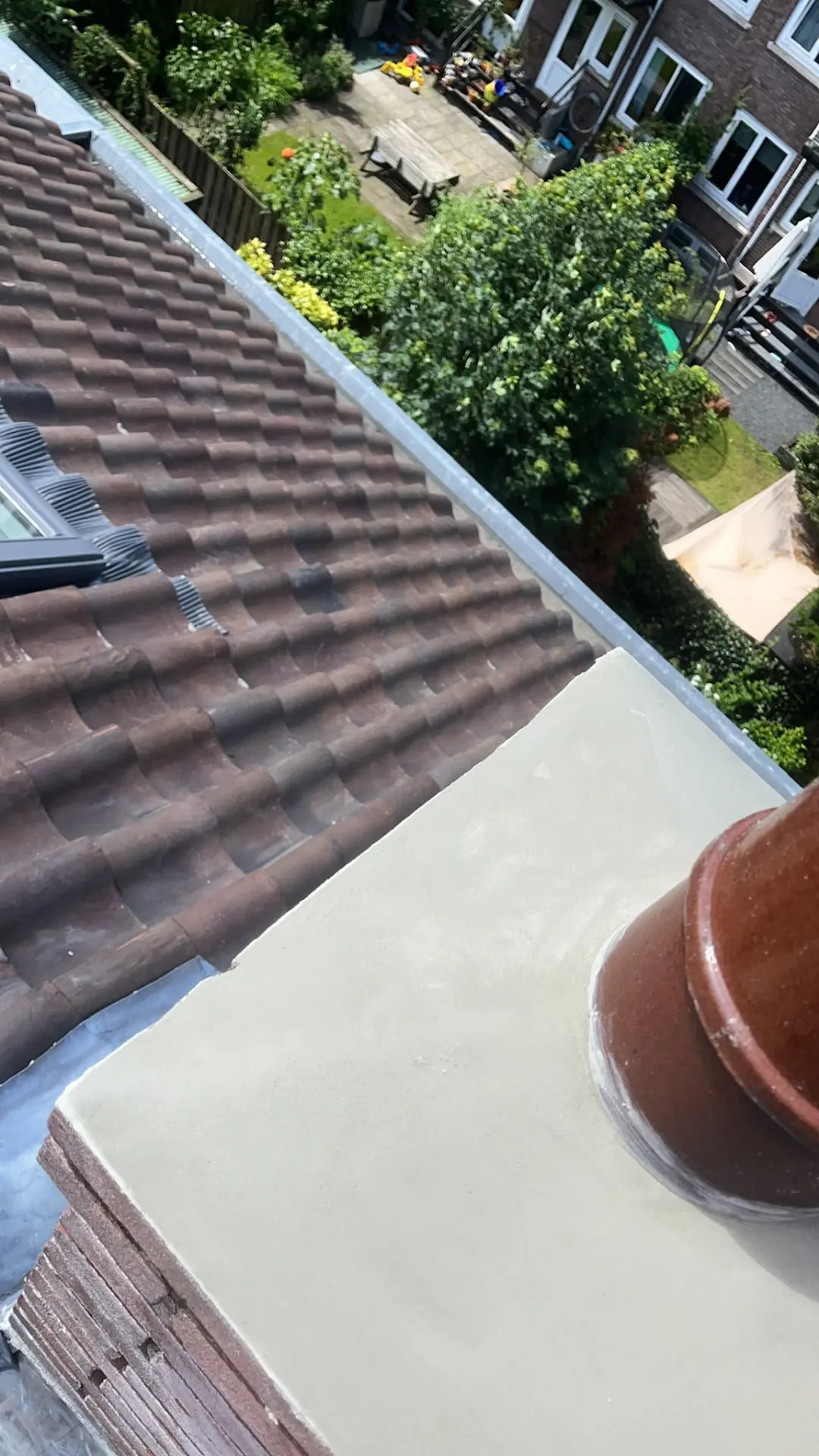 Gestucte schoorsteenafdekking boven een pannendak na herstel
