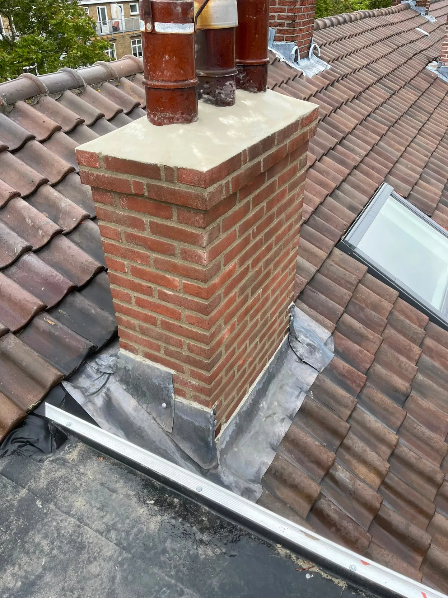 Herstelde schoorsteen met nieuw voegwerk en lood rond de schoorsteenvoet