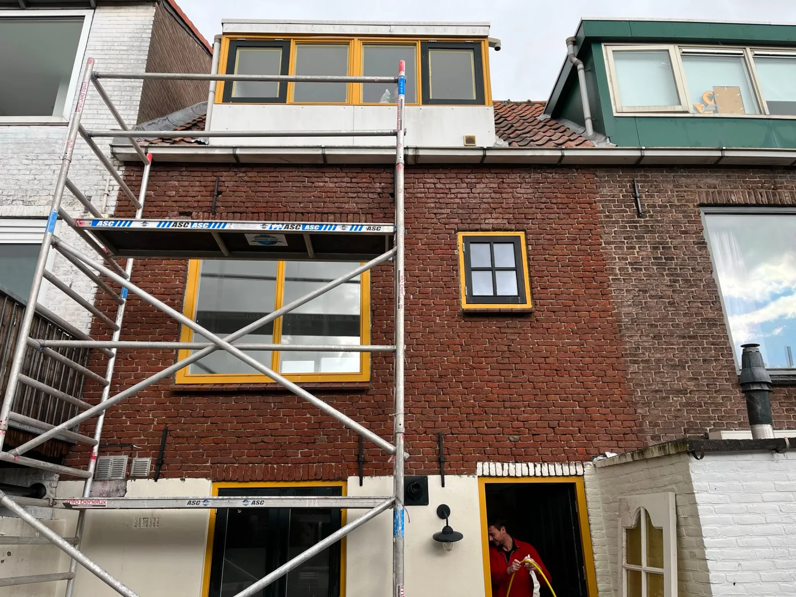 Rolsteiger bij een achtergevel tijdens gevelrenovatie en voegwerk