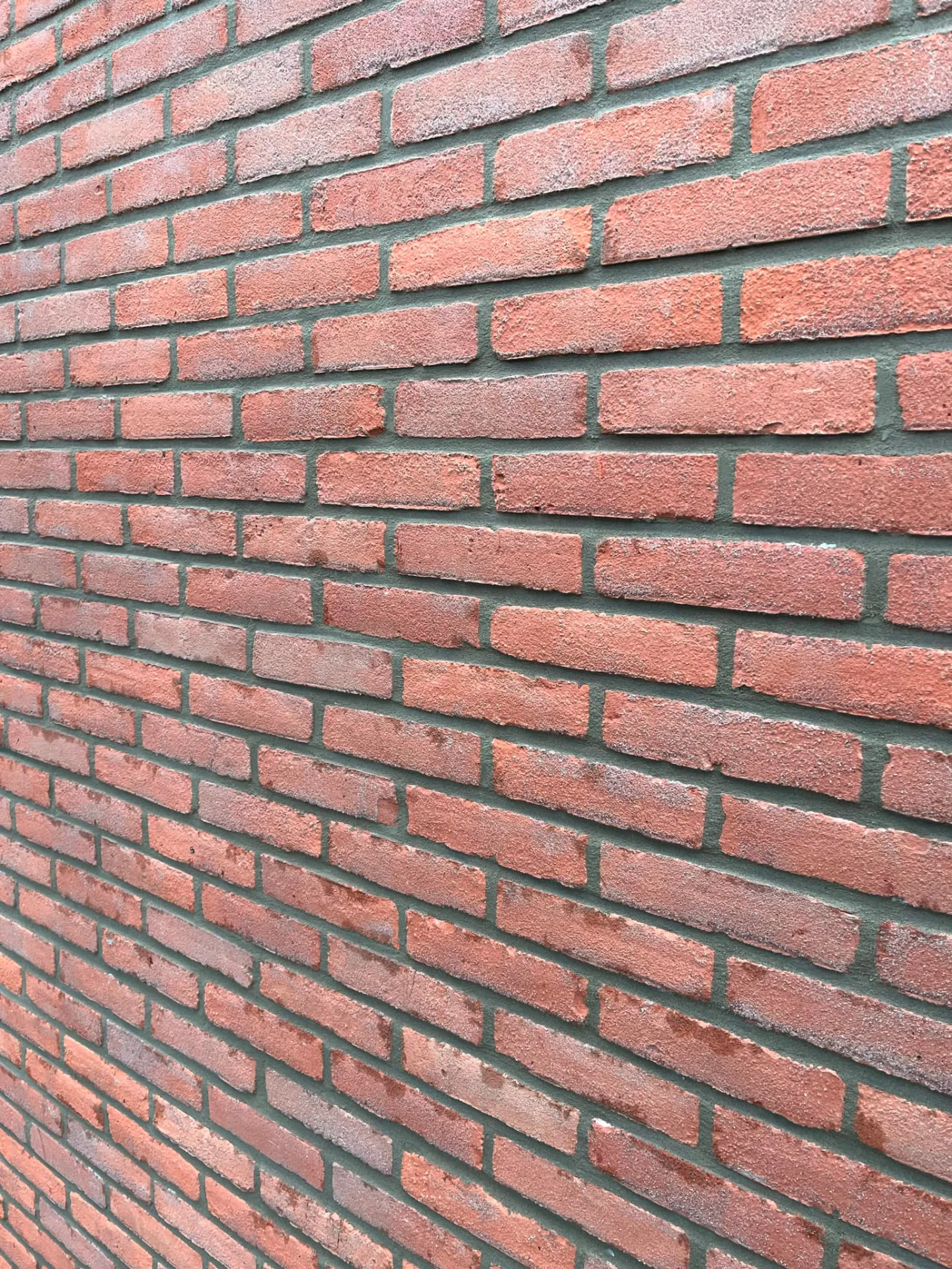 Detail van strak vernieuwd voegwerk in een rode baksteengevel
