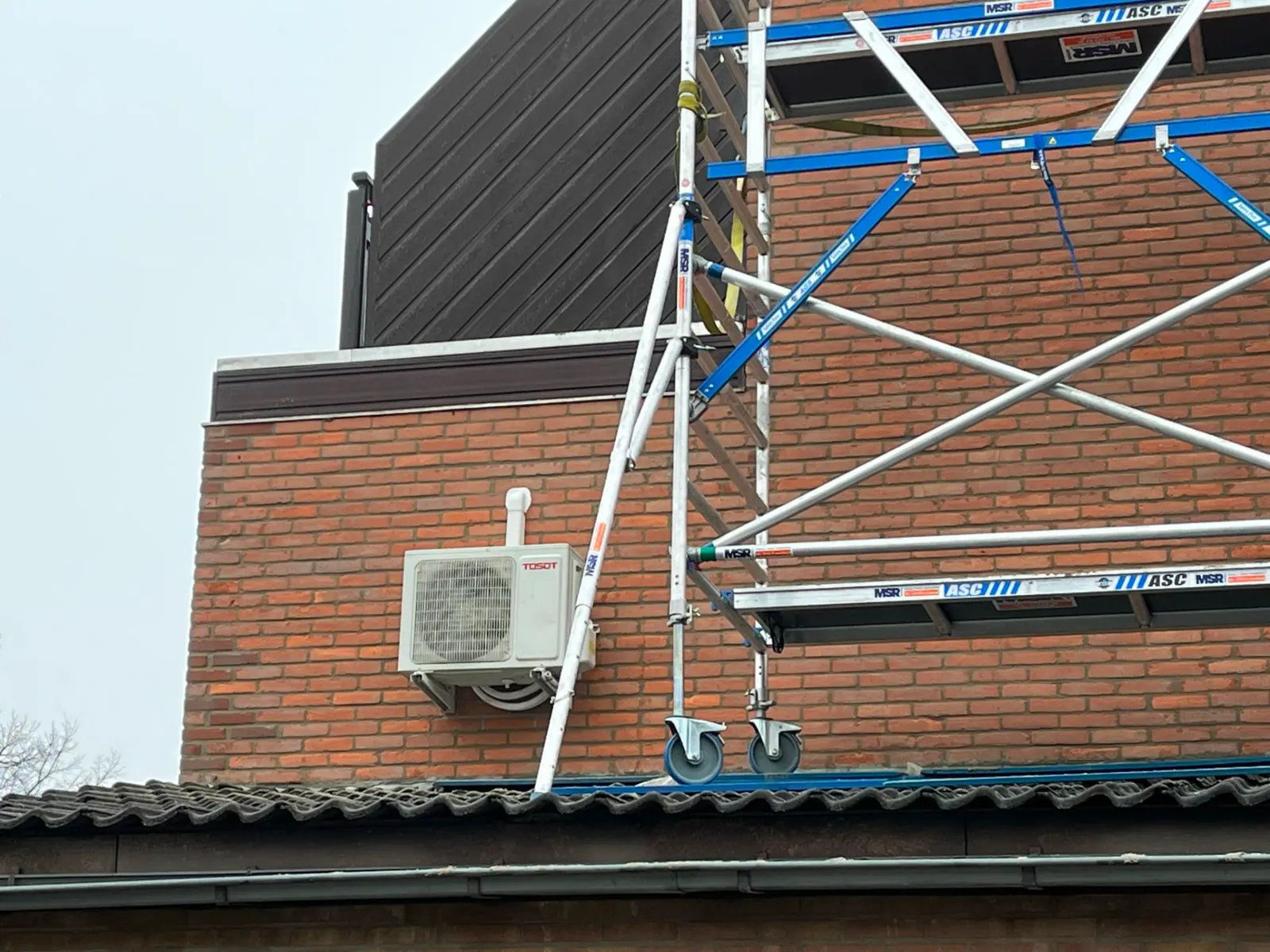 Rolsteiger tegen een rode bakstenen gevel tijdens gevelonderhoud