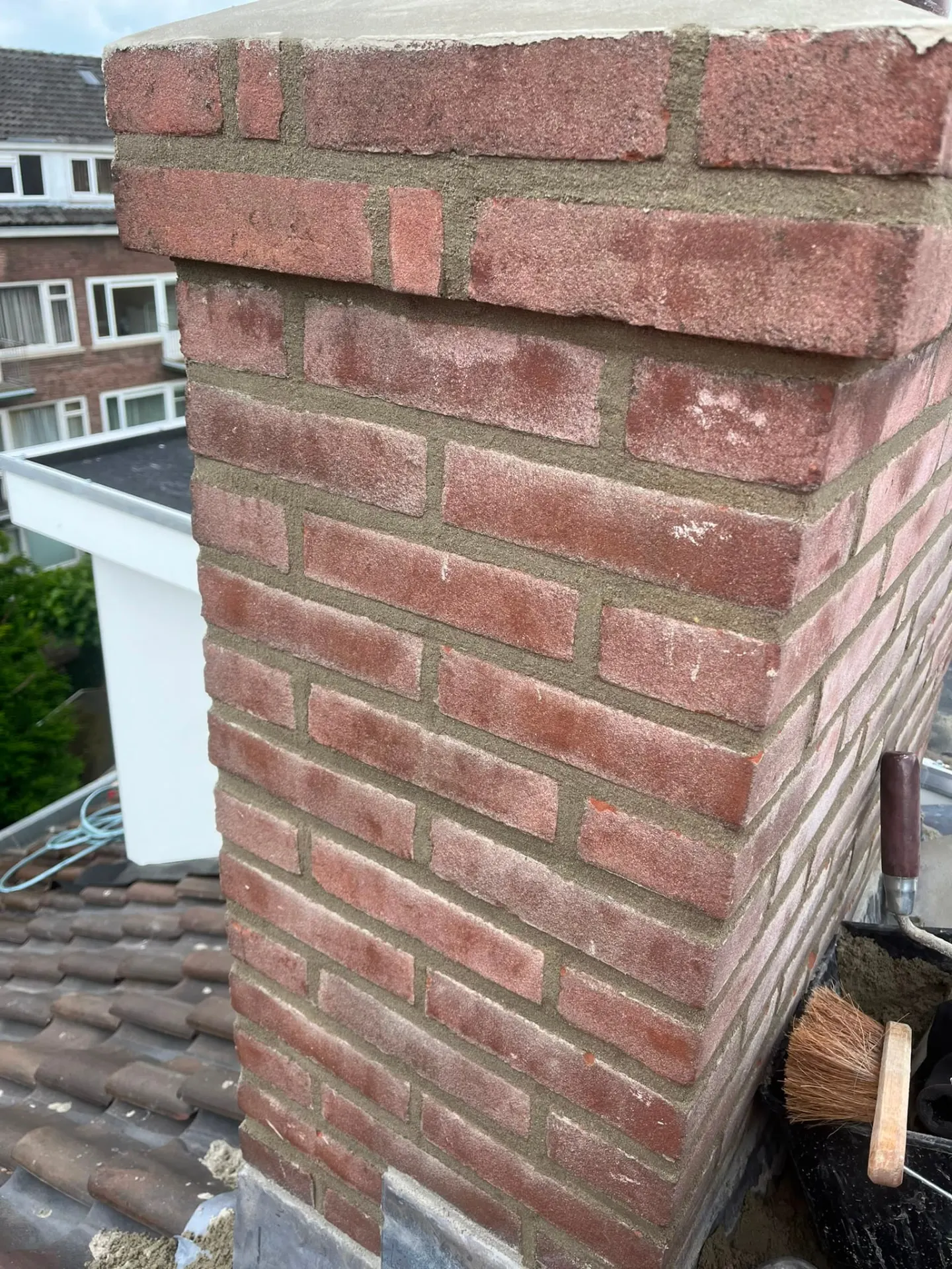 Opnieuw opgemetselde schoorsteen met vers voegwerk en nieuwe afdekking