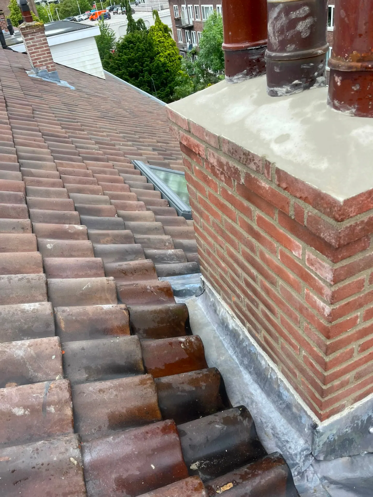 Schoorsteen met nieuw voegwerk en zinken aansluiting op een pannendak