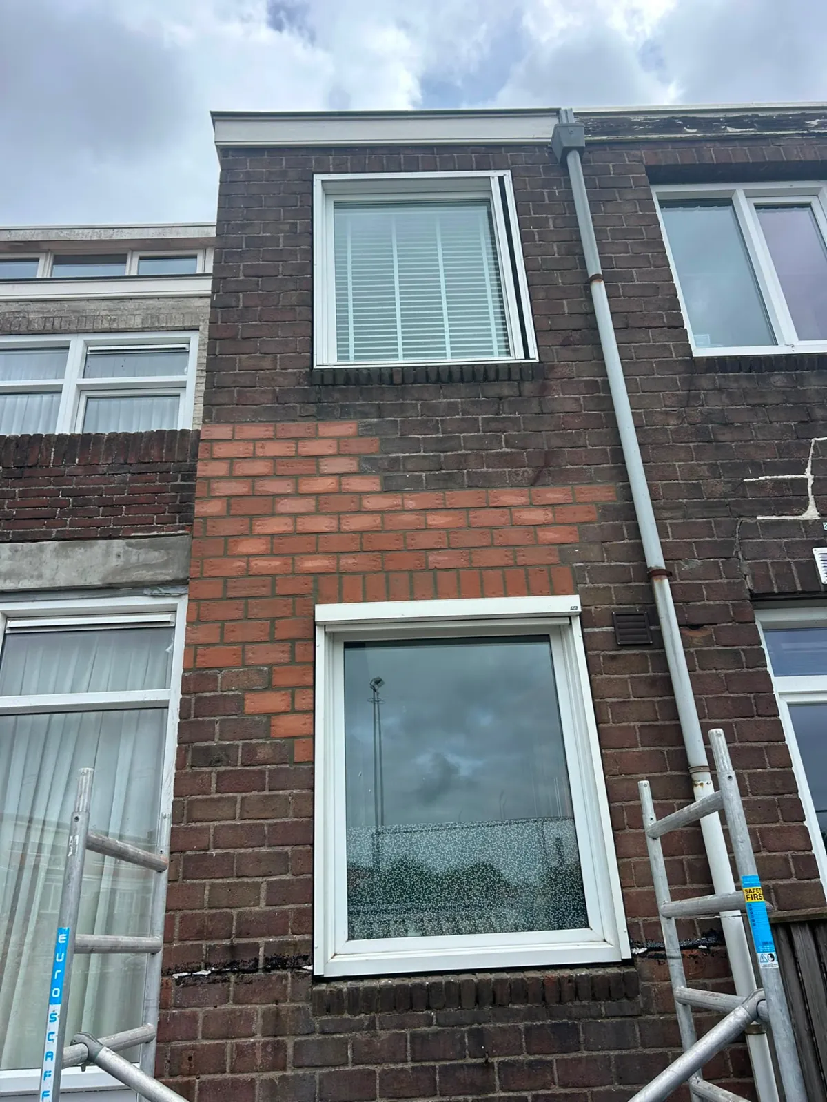 Gevel met nieuw ingeboet rood metselwerk na scheurherstel