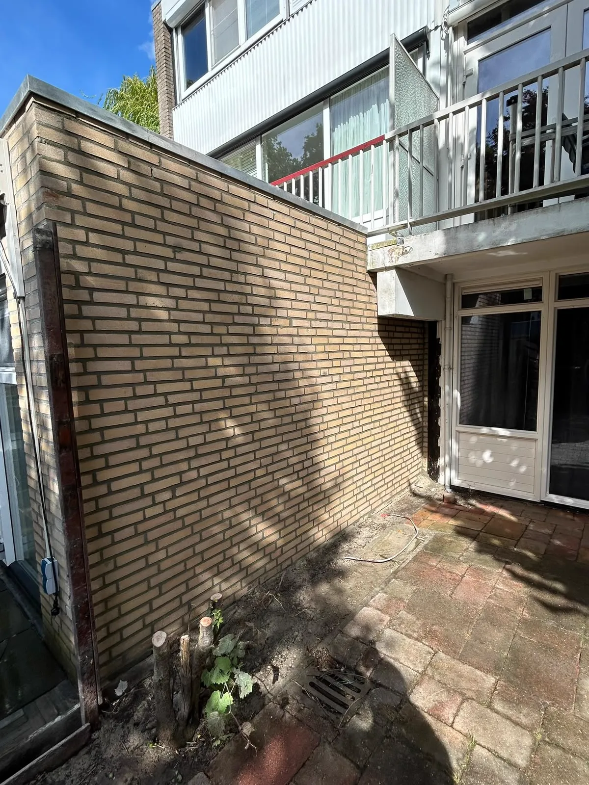 Gereinigde gele bakstenen zijgevel bij een woning met terras