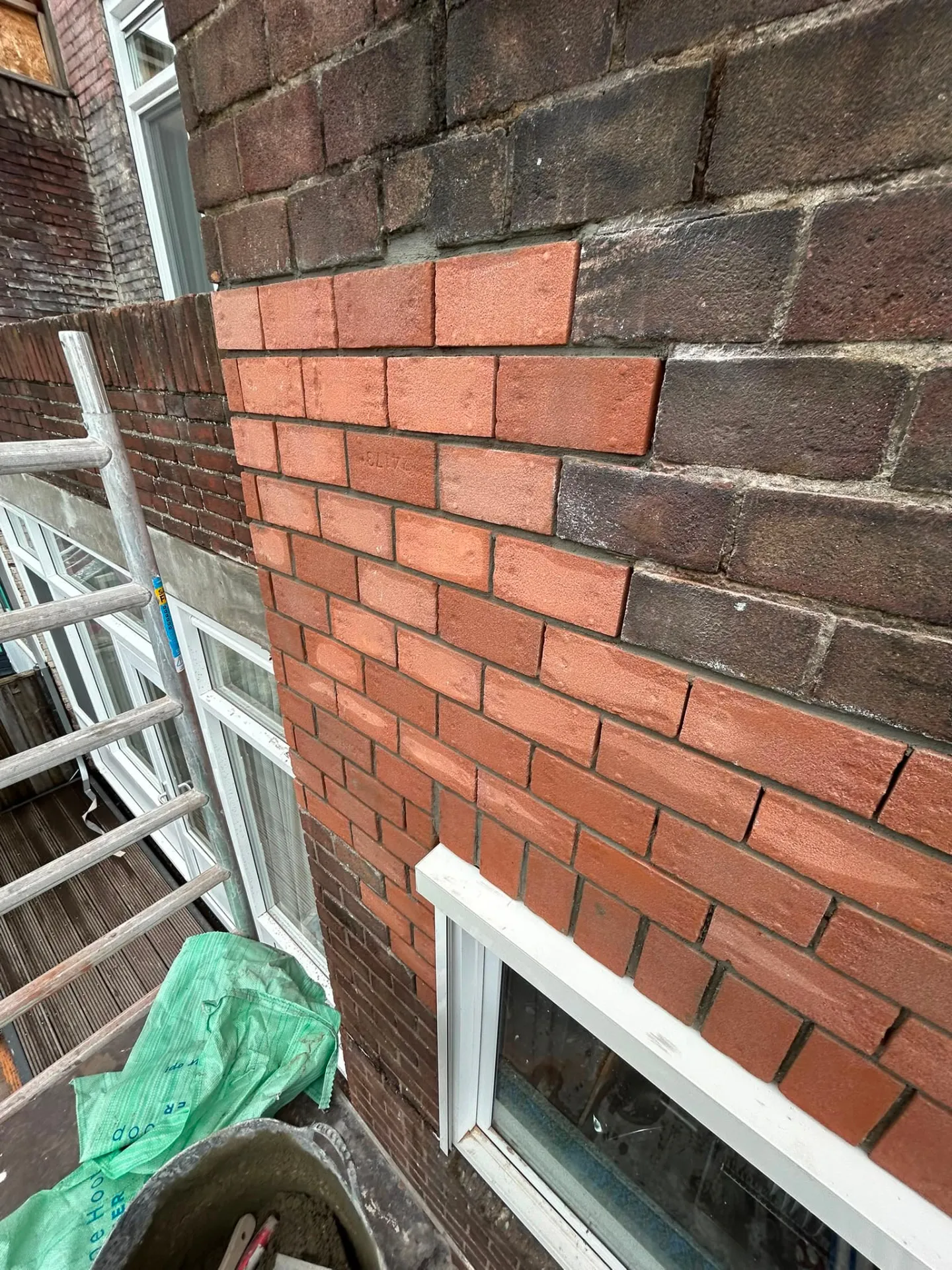 Nieuw ingeboet rood metselwerk in een bestaande gevel