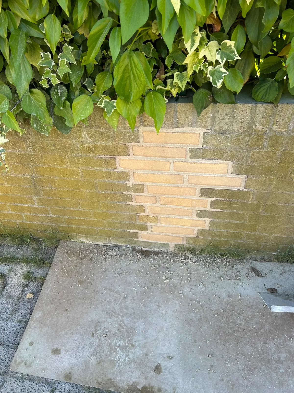 Inboetwerk met gele stenen in een tuinmuur na uithakken