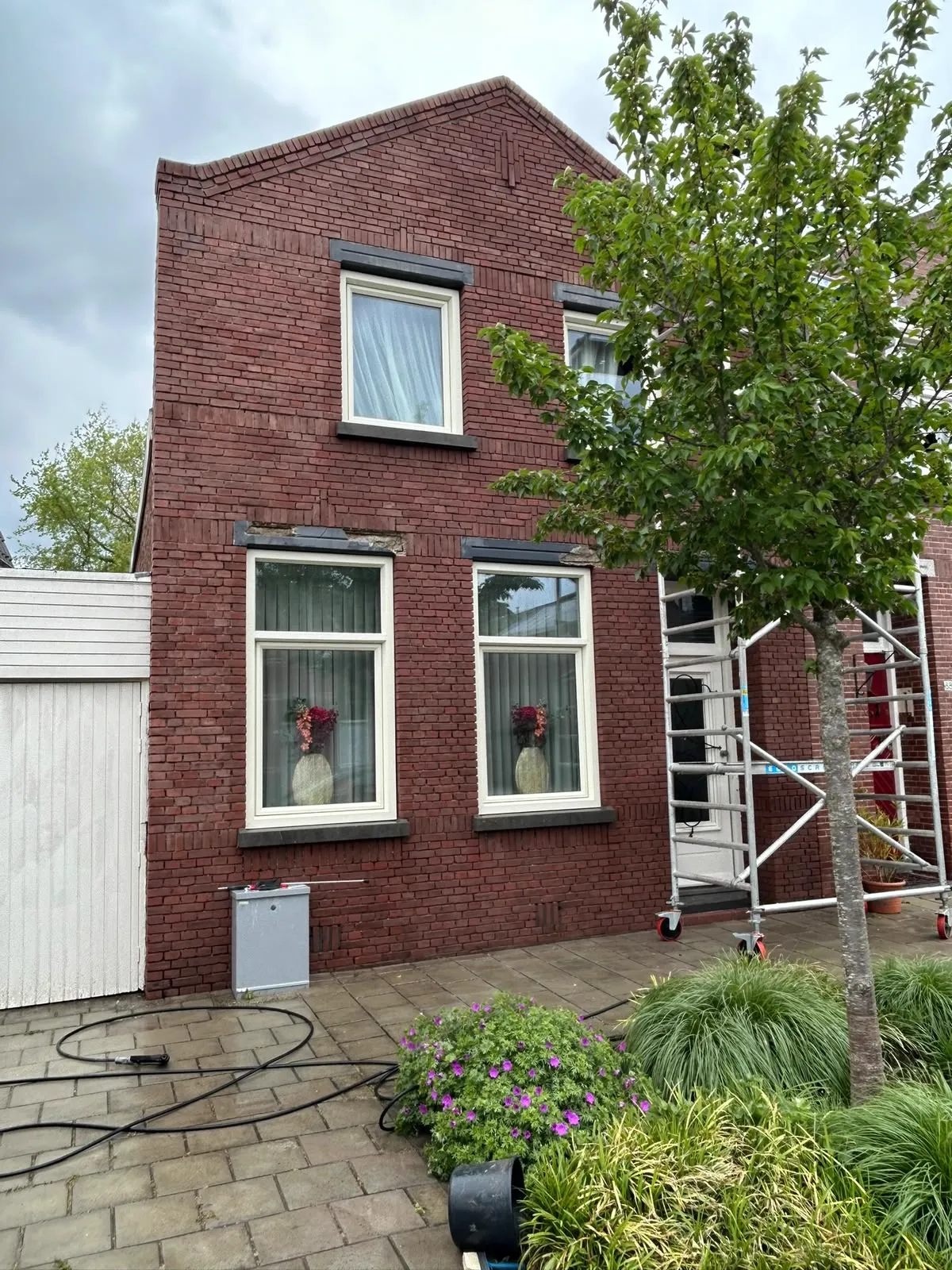 Rode bakstenen gevel voor renovatie van voegwerk en lateien