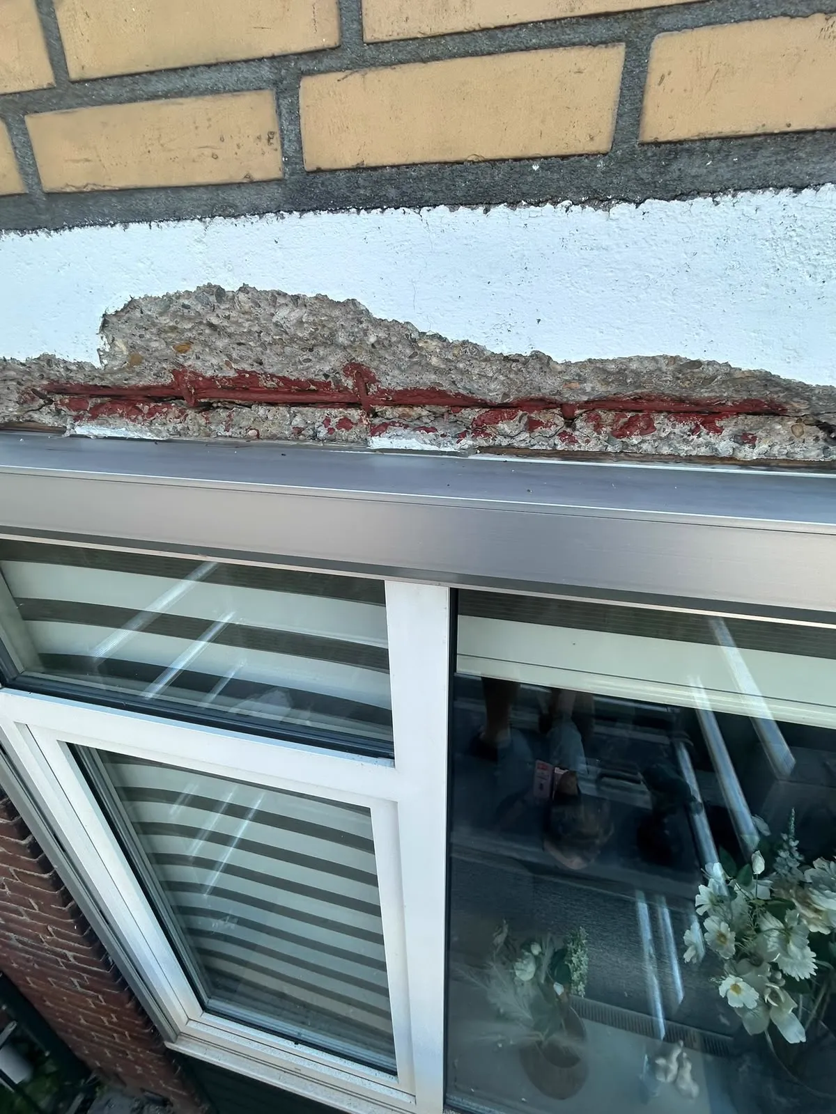 Betonrot in een latei boven een raamkozijn blootgelegd voor herstel