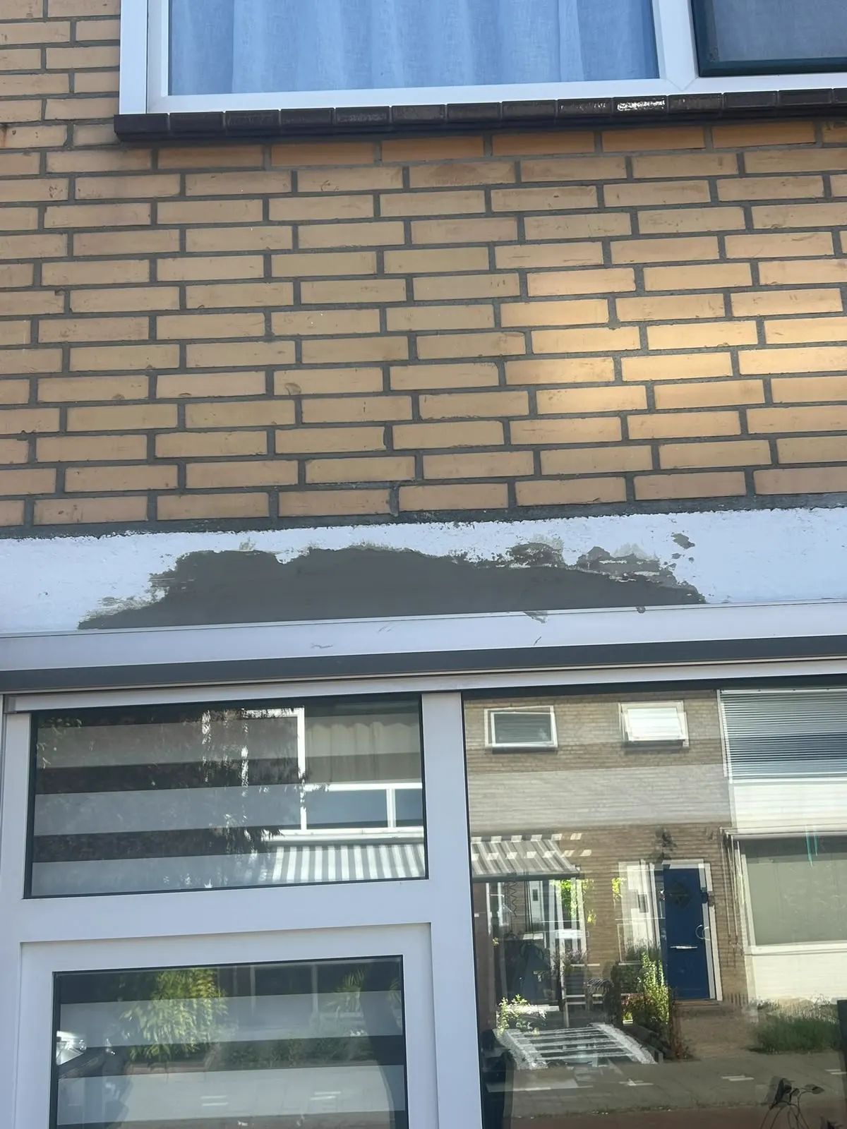 Betonrotherstel van de latei boven een pui in een gele gevel