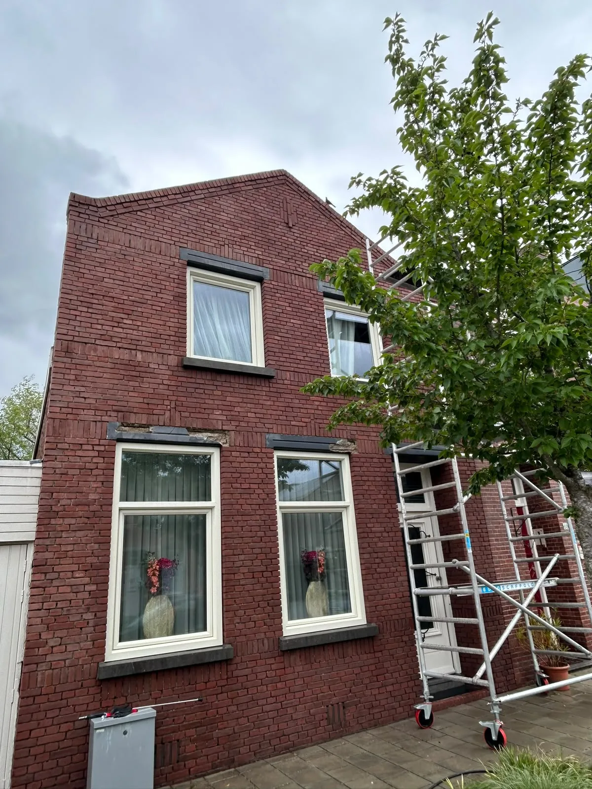 Rode bakstenen woning met rolsteiger tijdens gevelrenovatie