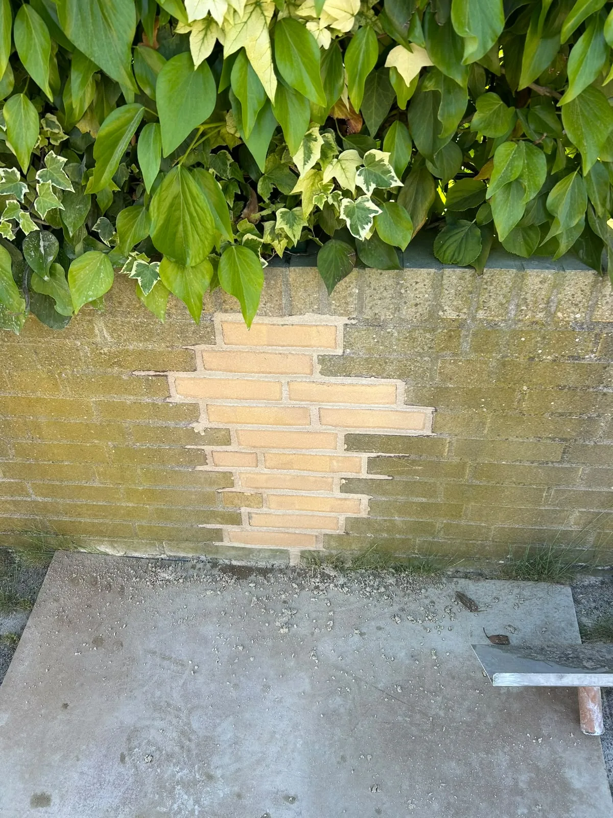 Inboetwerk met nieuwe gele stenen in een tuinmuur
